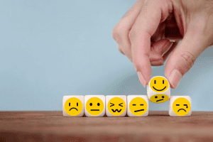 Person picking up cubes with emoji faces on them