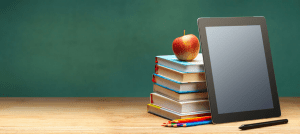 School supplies on a desk in front of a blackboard